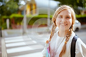 Smiling pupil in sweatshirt crossing crosswalk outdoors in city