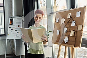 smiling queer person looking at folder