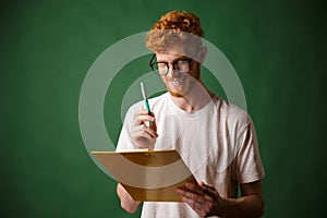 Smiling readhead bearded man in white tshirt holding folder and