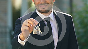 Smiling real estate agent showing house key, private property purchase ownership