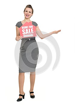 Smiling realtor with home for sale sign