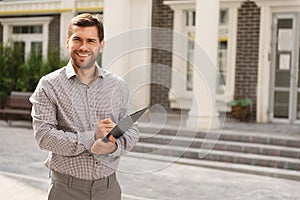 Smiling realtor standing outside modern house