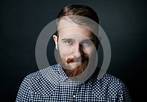 Smiling red bearded man studio portrait on dark background