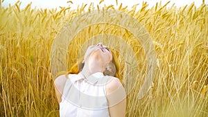 Smiling red haired girl daydreaming in wheat field in harvest season