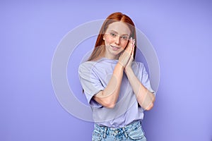 Smiling red-haired woman showing sleeping gesture