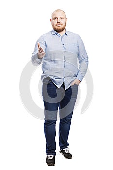 Smiling red-haired young man with a beard in a blue shirt and full-length jeans. Isolated over white background.