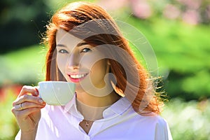 Smiling red headed woman cup coffee. Close-up portrait of young beautiful woman holding the cup of morning coffee over