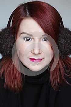Smiling redhead girl in ear muffs portrait