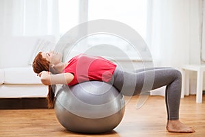 Smiling redhead girl exercising with fitness ball