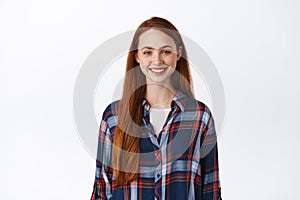 Smiling redhead girl with long hair, pale natural skin no make up, smile white teeth, standing in plaid shirt and