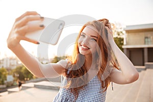 Smiling redhead girl with long hair taking a selfie