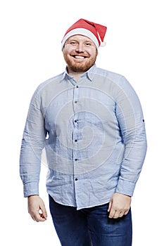 Smiling redhead man in santa claus hat. New Year and Christmas celebration. Isolated on a white background. Vertical