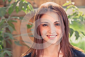 Smiling redhead teen. Front view closeup image of a smiling teenage girl outdoors against old wood plank background with leaves