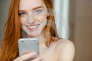 Smiling redhead woman holding smartphone