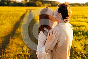 Smiling redhead young woman with closed eyes and unrecognizable man in love hugging, kissing, stroking standing together