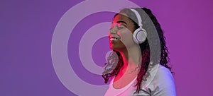 Smiling Relaxed Black Lady Listening Music In Wireless Headphones Under Neon Light