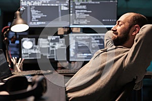 Smiling relaxed coder sitting laid back on chair