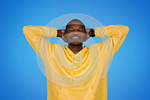Smiling relaxed millennial african american guy in sweatshirt resting with closed eyes