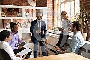 Smiling relaxed millennial diverse teammates involved in friendly conversation.