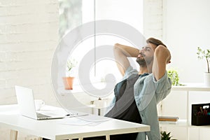 Smiling relaxed worker leaning back in chair during work break