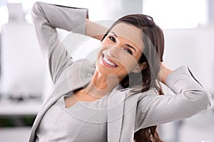 Smiling and relaxed young business woman leaning back on chair in a modern office portrait. Confident, formal and