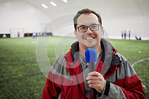 Smiling reporter with microphone on covered sports photo