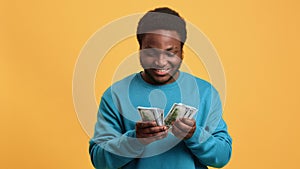 Smiling rich African American man checking cash money dollar earnings and financial success isolated