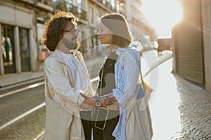 Smiling romantic couple in love holding hands while standing on old city european street on sunset