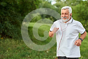 Smiling running old man in green city park.