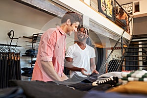 Smiling Sales Assistant Helping Male Customer To Buy Clothes In Fashion Store