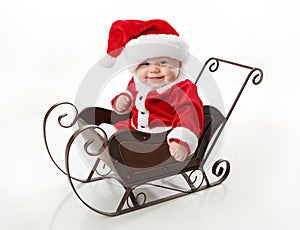 Smiling santa baby sitting in a sleigh photo