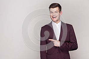 Smiling satisfied man pointing aside at copy space for advertisement or promotional text.