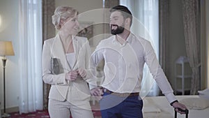 Smiling satisfied man and woman hugging in luxurious hotel room. Portrait of excited Caucasian clients in high-class