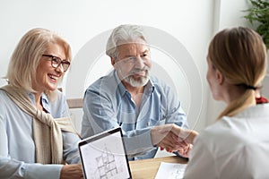 Happy older family and realtor shake hands buying new house photo