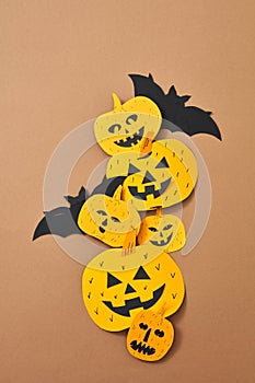 Smiling scary pumpkins and bat handcraft of paper on a brown background with space for text. Halloween. Flat lay