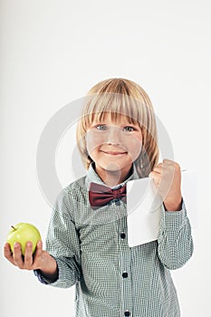 Smiling School boy in shirt with red bow tie, holding tablet computer and green apple in white background