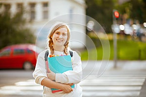 Smiling school girl crossing crosswalk and going to school