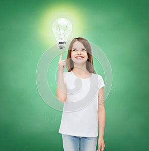 Smiling school girl pointing finger to light bulb