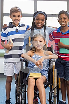 Smiling school kids standing with arm around in library