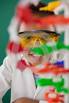 Smiling schoolboy experimenting molecule model in laboratory