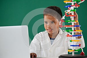 Smiling schoolboy experimenting molecule model in laboratory