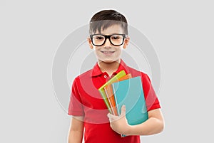 Smiling schoolboy in glasses with books