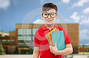 Smiling schoolboy in glasses with books