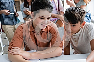 Smiling schoolboy looking at blurred digital