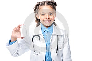 smiling schoolchild in costume of doctor holding bottle of pills
