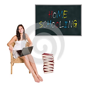 Smiling schoolgirl with a huge pile of books and a laptop in front of a blackboard