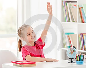 Smiling schoolgirl raising hand during lesson