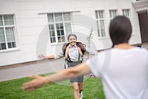 Smiling schoolgirl running to meet mom