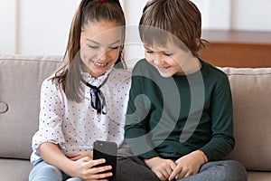 Smiling schoolgirl showing funny video in social networks to brother.