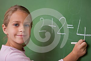Smiling schoolgirl writing a number